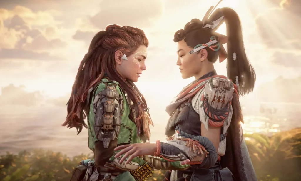 Une capture d'écran du jeu vidéo Horizon Forbidden West Burning Shores du personnage LGBTQ+ Aloy debout bras dessus bras dessous avec un autre personnage féminin qu'elle a embrassé