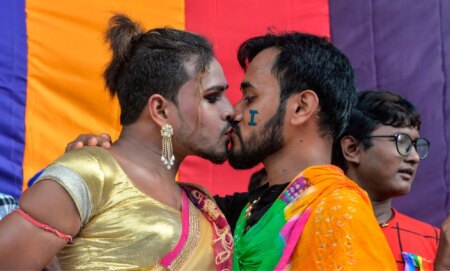 Two LGBTQ+ Indians kiss during a Pride parade.