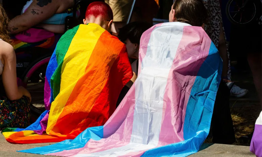 Deux militants portant des drapeaux LGBTQ+ lors d'un événement de la fierté.