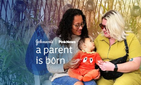 This is an image with 2 women holding a baby. The woman on the left is wearing a grey jumper. She has long dark hair and is wearing glasses. The woman on the right has bright blonde hair and is wearing sunglasses. The baby in the middle is wearing an orange onesie. Over the image in white text reads "JOHNSON'S, PINKNEWS A PARENT IS BORN"