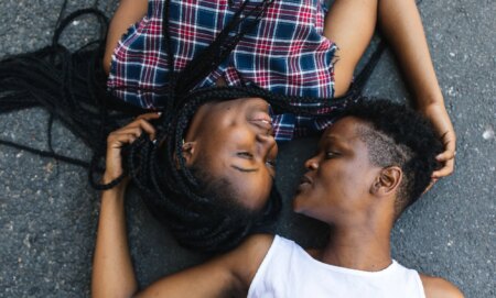 Two black lesbians lying down opposite each other