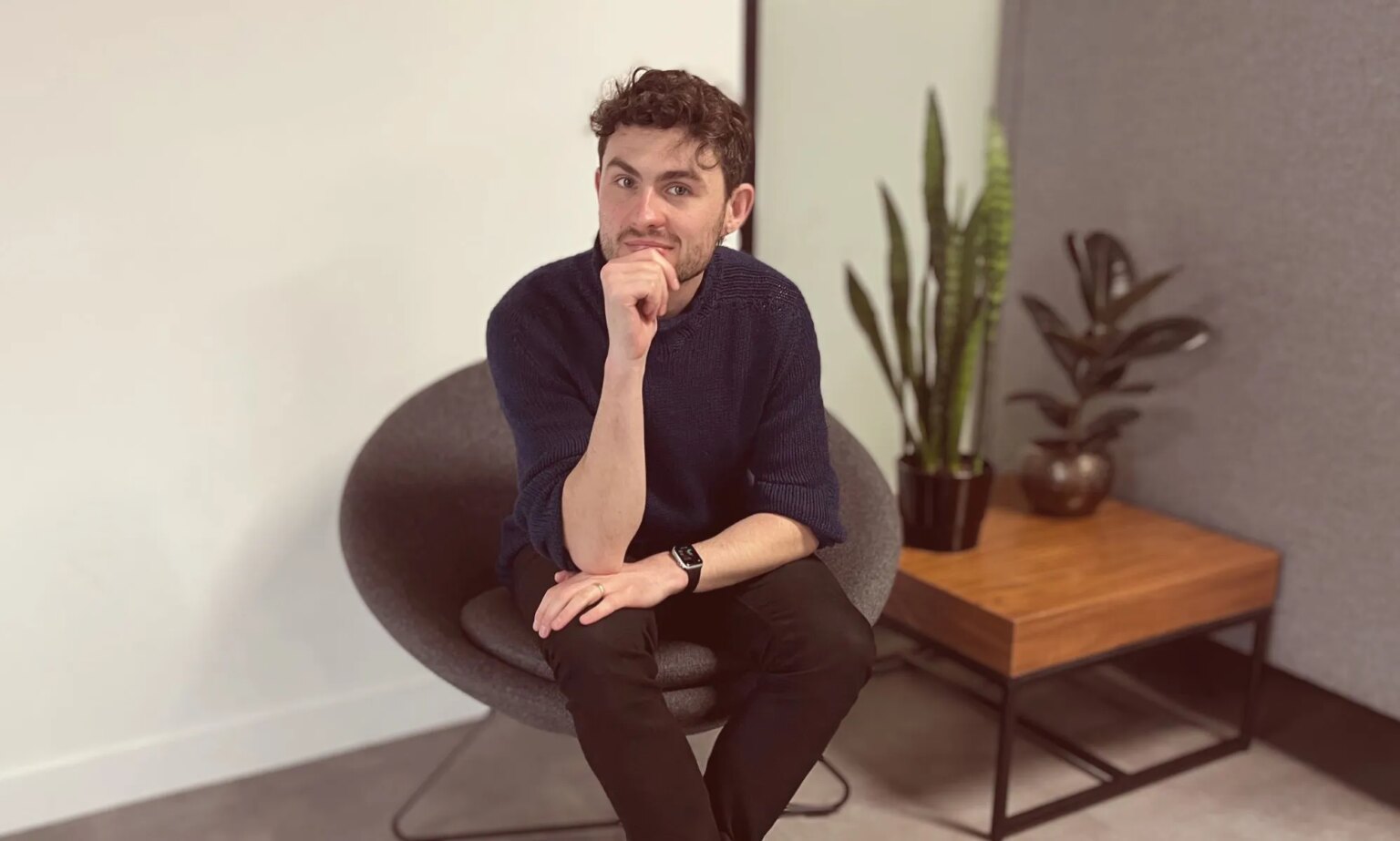 «Leçons que j’ai apprises en tant qu’entrepreneur queer» This is an image of a white man sitting in an office. He has on dark clothing