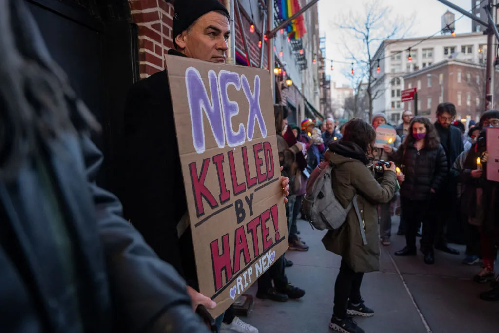 Des gens se rassemblent devant le Stonewall Inn pour un mémorial et une veillée en hommage à l'adolescent de l'Oklahoma décédé à la suite d'une bagarre dans les toilettes d'un lycée le 26 février 2024 à New York.  Nex Benedict, un jeune de 16 ans qui s'est identifié comme non binaire et a utilisé des pronoms, est décédé un jour après l'altercation dans les toilettes de l'école.  Un manifestant tient une pancarte indiquant « Nex, tué par la haine »