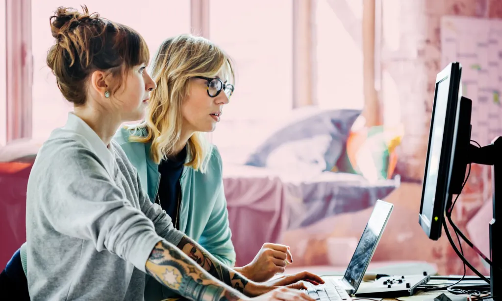 Il s'agit d'une image de deux femmes travaillant devant un ordinateur.