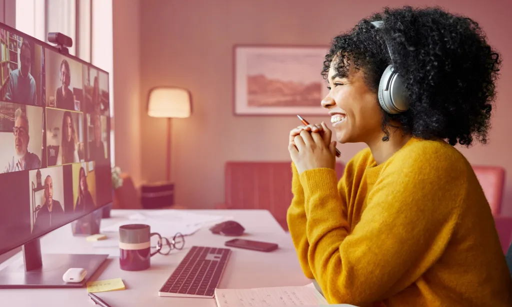 Il s’agit d’une image d’une femme noire assise devant un ordinateur chez elle.  Elle est en appel Zoom.
