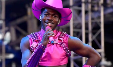 Lil Nas X performs in a hot pink outfit and matching cowboy hat holding a hot pink microphone