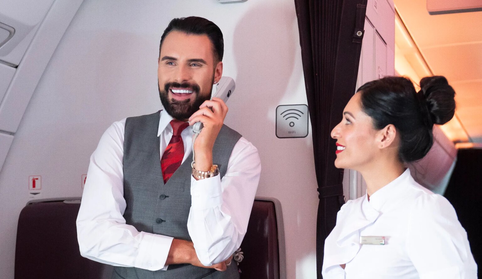 Rylan Clark réalise son rêve d'enfant de travailler comme équipage de cabine sur un vol Virgin Atlantic Rylan Clark holding an in-flight phone while working as Virgin Atlantic cabin crew