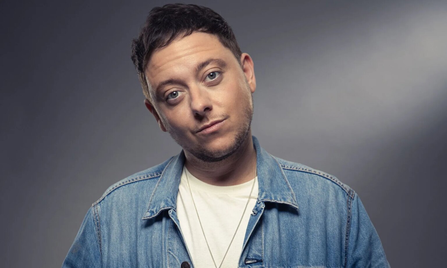 La star d'Emmerdale, Ash Palmisciano, explique pourquoi montrer l'amour trans à l'écran est « incroyablement important » Emmerdale star and out trans actor Ash Palmisciano wears a white shirt and blue button up over it as he stares towards the camera