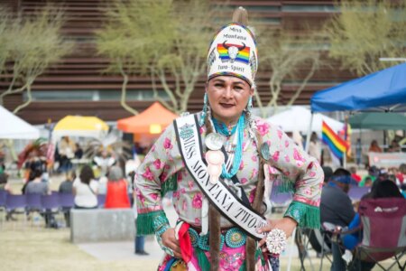 A Two Spirit person dances at an event in elaborate traditional dress