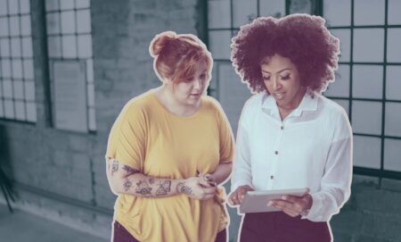 This is an image of two women looking down on an ipad.