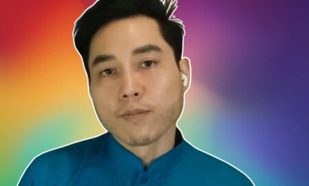 A screenshot of Andy Ngo infront of a rainbow background.
