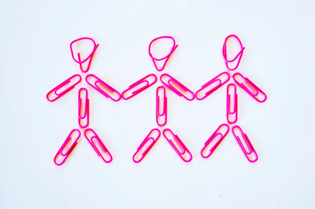 Une idée conceptuelle d'une relation lesbienne polygame.  Trois femmes se tenant la main, les bras baissés.  Représenté par des couleurs roses stéréotypées pour les filles, il représente également le bonheur, les modes de vie alternatifs et la simplicité.  Prise de vue en studio sur fond blanc.