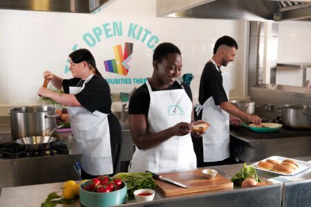 This is an image of three people preparing food in a kitchen
