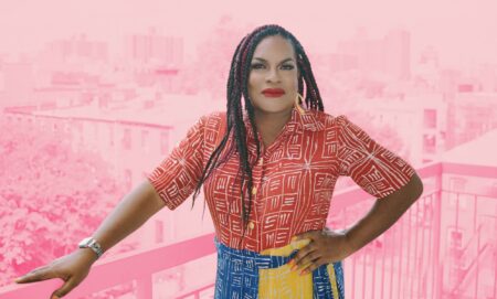 This is an image of a Black trans woman named Imara Jones. She is wearing a red shirt and a colourful skirt.