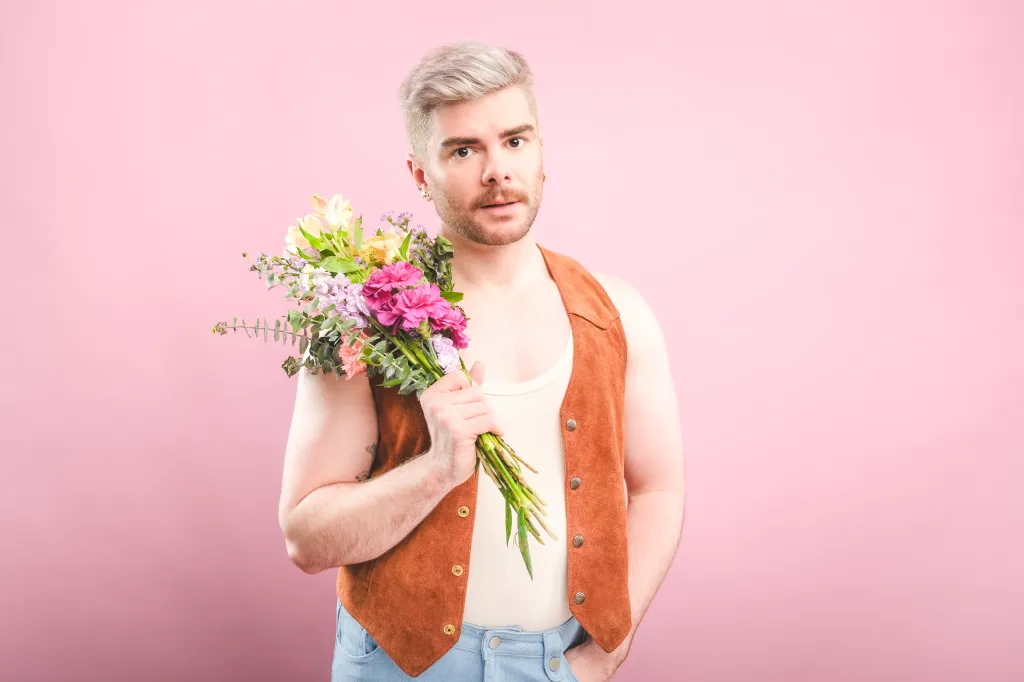 Chris Hall : Girl For All Seasons au festival Fringe d'Édimbourg. Chris tient un bouquet de fleurs sur un fond rose pâle.