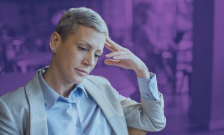 This is an image of an LGBTQ+ professional looking depressed or stressed. She is wearing a khaki suit.