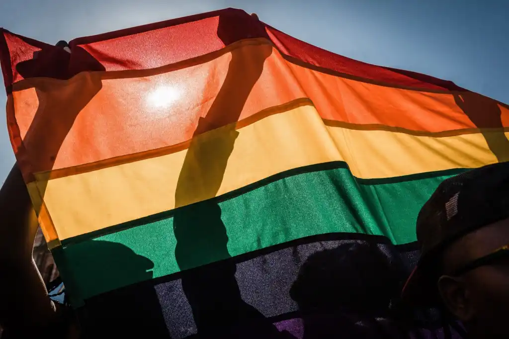 Des gens brandissent un drapeau de la fierté LGBTQ+