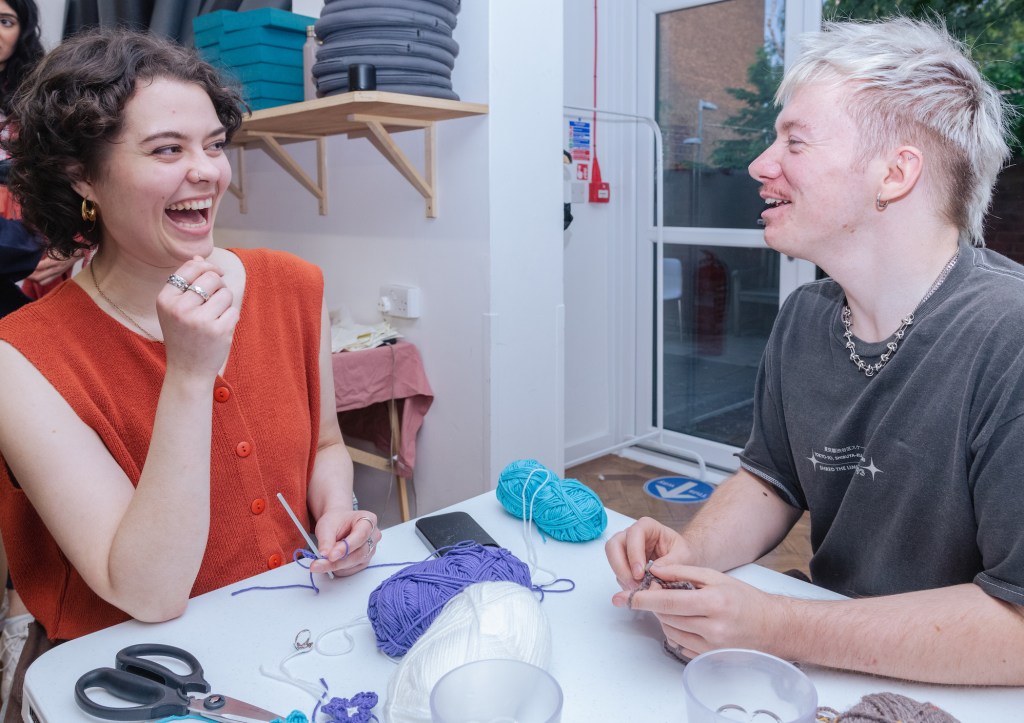 Deux membres de Queer Craft rient en créant ensemble