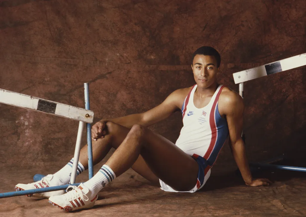 Portrait du coureur de haies Colin Jackson de Grande-Bretagne le 1er juin 1987. Colin est assis sur le sol sur un fond marron, en tenue de sport, entre deux haies