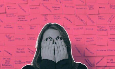 This is an image of a women with her hands covering her face in front a bunch of workplace jargon terms. She is in black and white.