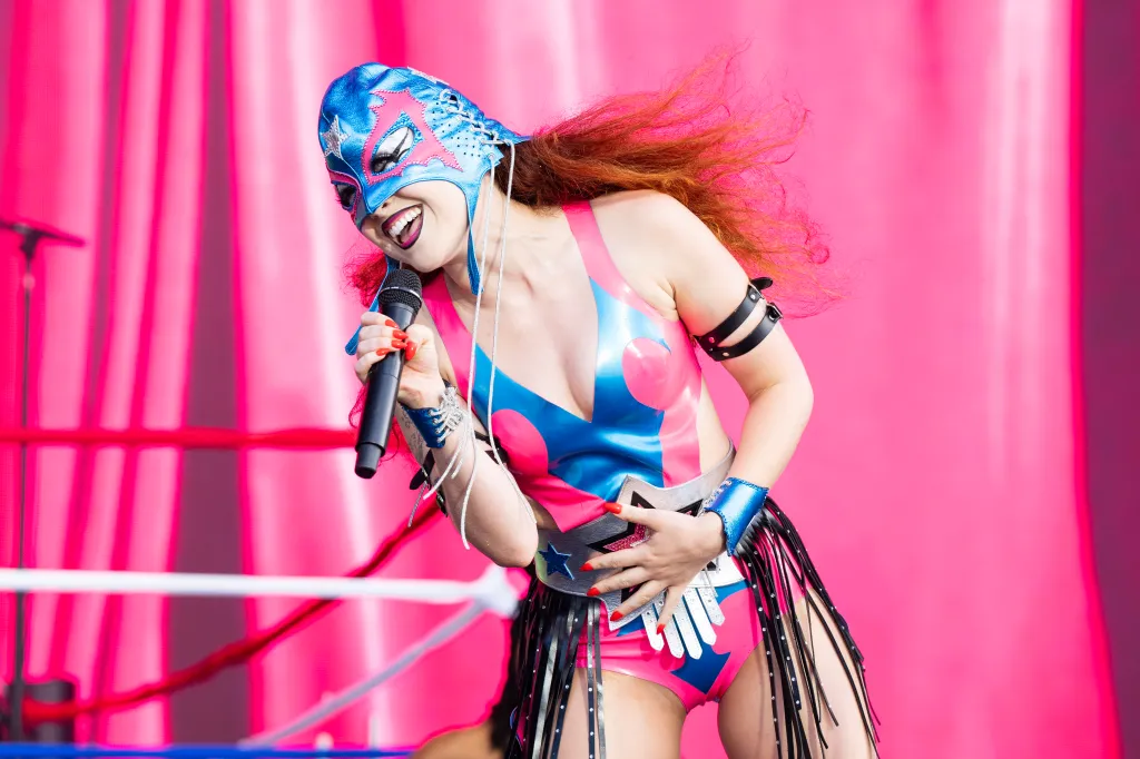 Chappell Roan se produit sur un fond rose vif au festival Lollapalooza, dans une tenue de lutteur