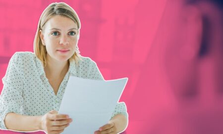 This is an image of a white woman with shoulder length blond hair holding a piece of paper. The background is a blurred out meeting room and is stylised in fuschia.