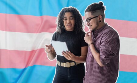 This is an image of two trans employees looking down at a tablet over the trans pride flag.