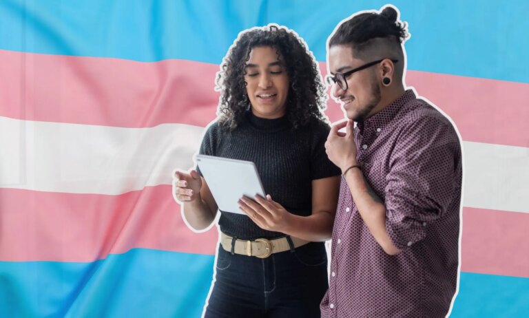 This is an image of two trans employees looking down at a tablet over the trans pride flag.