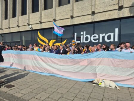 Liberal Democrats party members unfurling giant trans flag outside the Brighton Centre