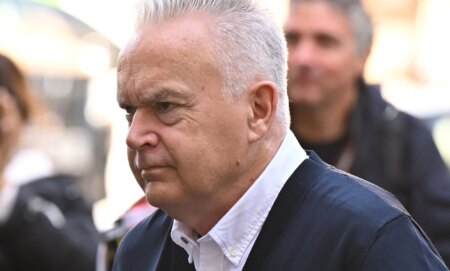 Huw Edwards in a crowd entering a court room.