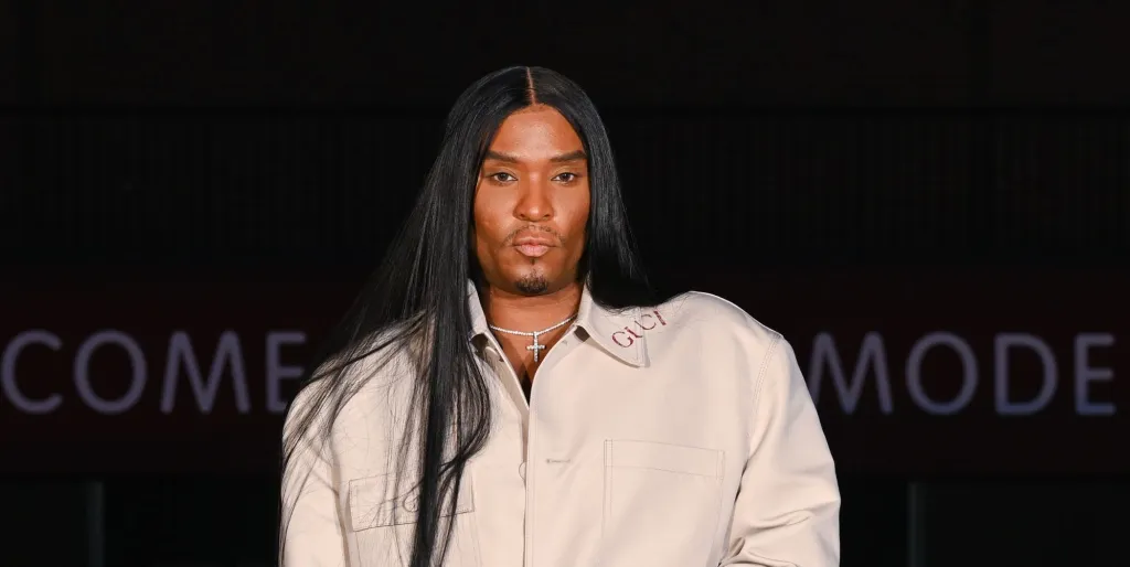 Law Roach aux longs cheveux noirs et portant une veste beige.