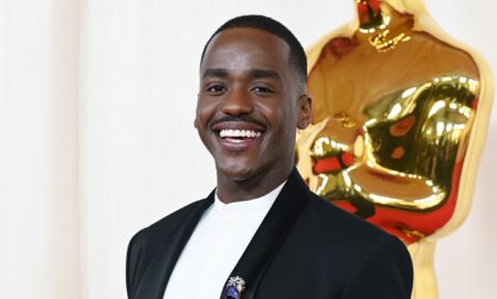 Ncuti Gatwa smiles while wearing a white shirt and black blazer.