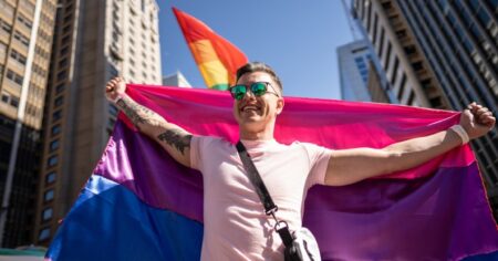 Un homme tenant un drapeau de la fierté bisexuelle