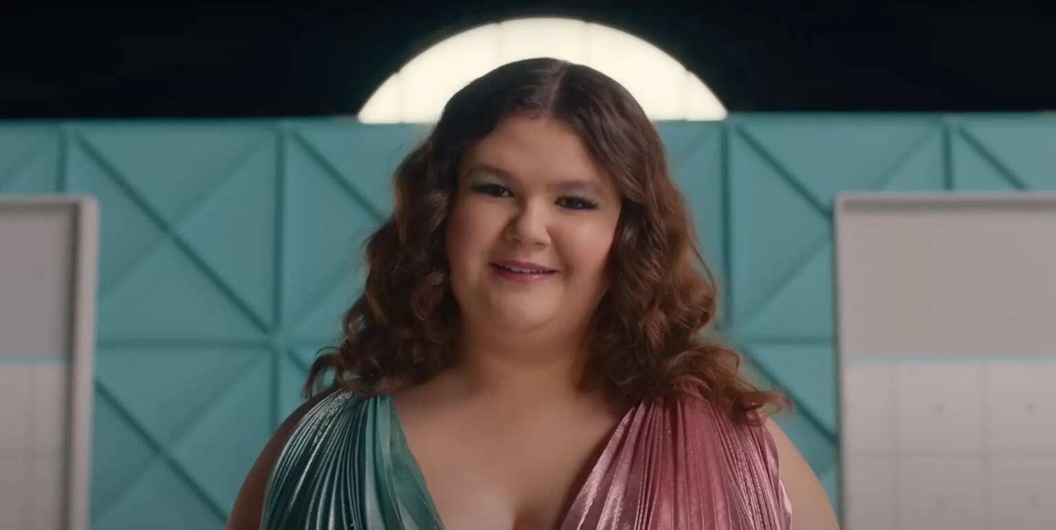 La star d'Empire Waist, Mia Kaplan : « Je n'ai jamais vu de personnages homosexuels de grande taille » A still from Empire Waist showing Mia Kaplan as Lenore smiling.