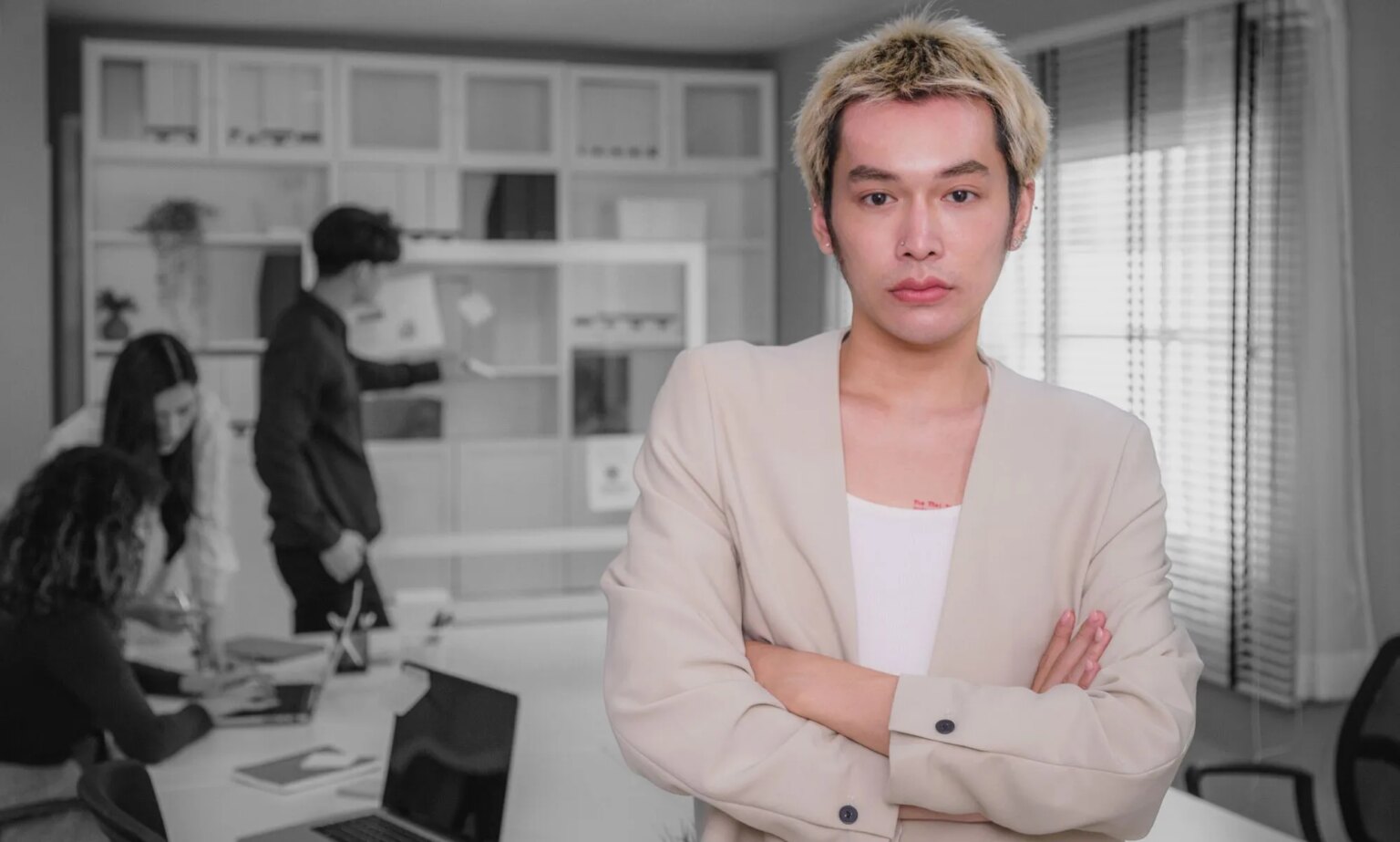 La Manchester Pride publie un guide « Coming Out at Work » pour aider le personnel LGBTQ+ et leurs employeurs Portrait of young Asian people Non-Binary person standing with arms crossed and colleagues working together in background while discussing on new project at modern office, Corporate business meeting and Successful partners teamwork, Employees engagement and white-collar worker, Finance and Economy, Global Business and Strategy, Looking at camera