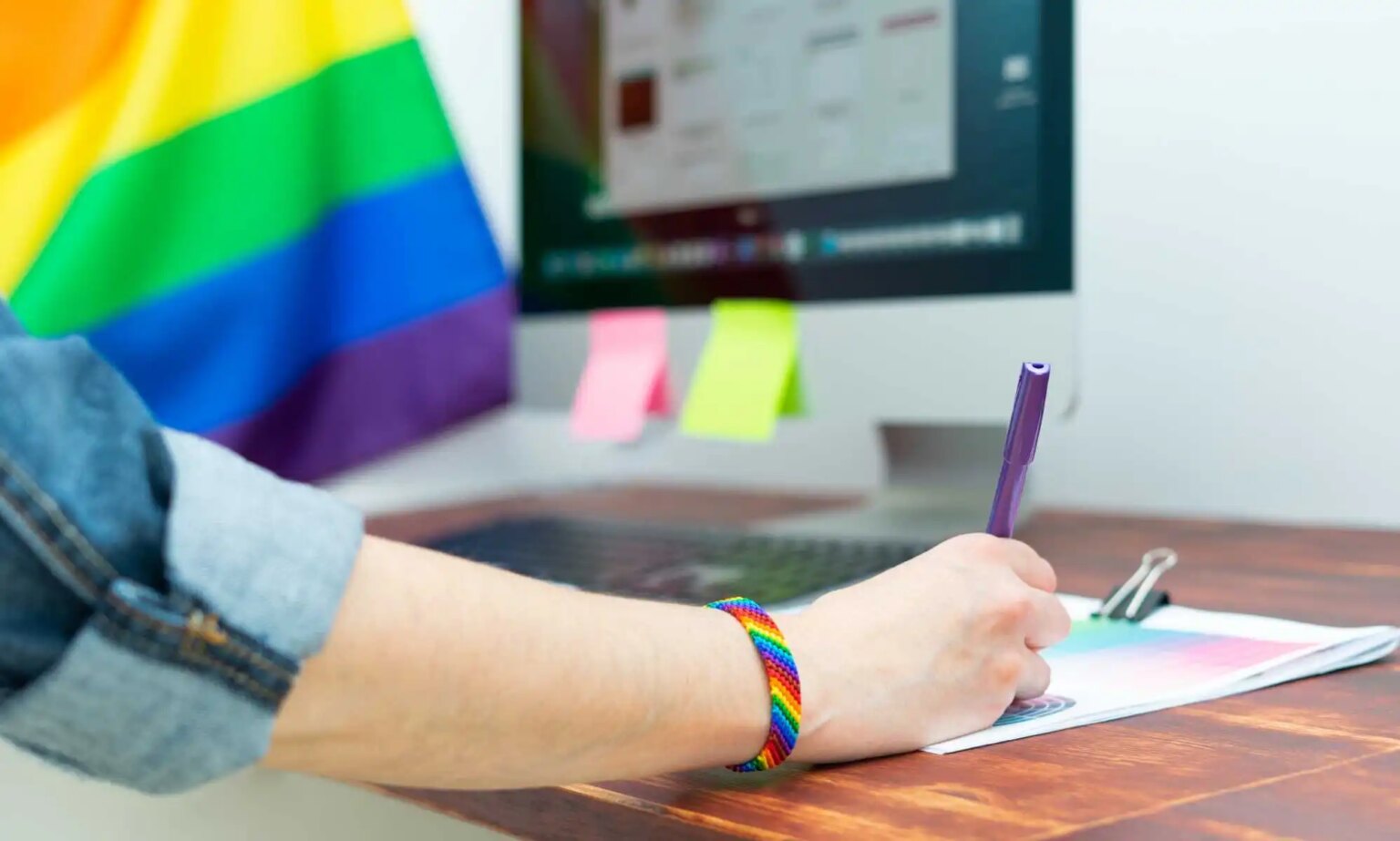 40 % des travailleurs LGBTQ+ sont dénoncés sans leur consentement – comment les employeurs peuvent-ils offrir leur soutien ? Woman's hand working in office with LGBT decor and accessories. Cultura LGBTQIA