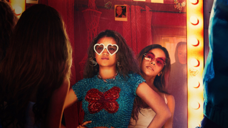 Time Cut still; two sisters posing in the mirror with glasses, a masked figure behind them