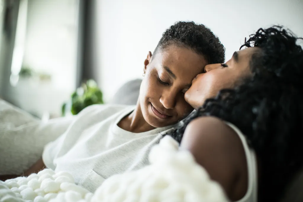 Couple de lesbiennes à la maison se blottissant sous une couverture