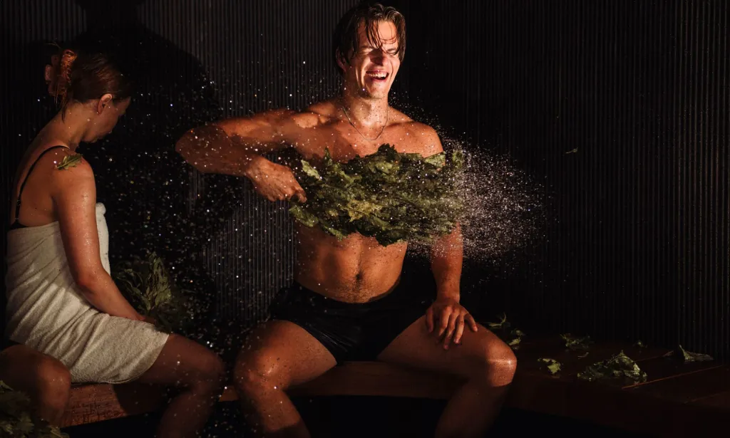 Un maître de sauna frappant des branches d'arbre contre sa poitrine.