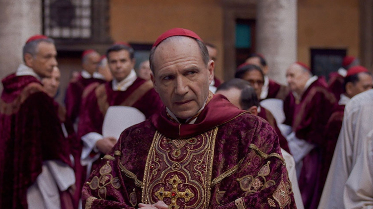 Les gens comparent ce film sur une élection papale à Drag Race : « Conclave Untucked quand ? Ralph Fiennes in Conclave as Cardinal Thomas Lawrence in a red and gold robe.