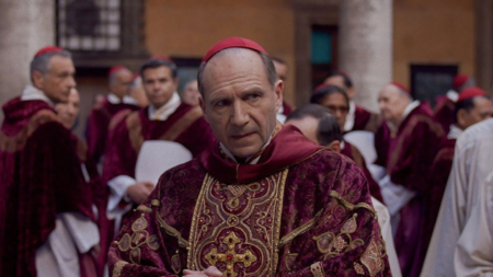 Ralph Fiennes in Conclave as Cardinal Thomas Lawrence in a red and gold robe.
