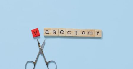 Lettres de Scrabble épelant « vasectomie » avec des ciseaux entre le « v » et le « a ».