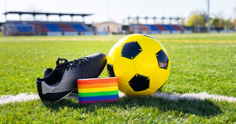 Un quart des personnes LGBTQ+ ne se sentent pas les bienvenues lors d'événements sportifs en direct, selon une étude Couleurs arc-en-ciel de la fierté LGBTQ+ sur un brassard à côté d'un ballon de football et d'une chaussure de football.