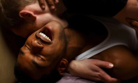 Gay men kissing on a sofa.