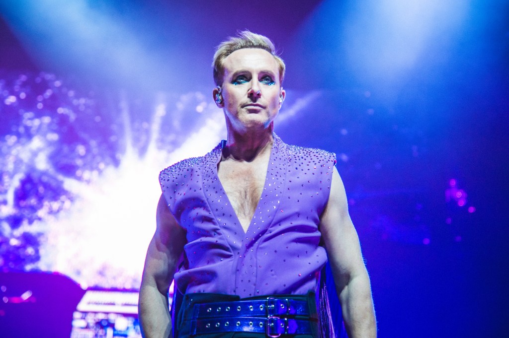 Ian "H" Watkins of Steps se produit à l'O2 Arena. Il porte une chemise violette décolletée recouverte de pierres précieuses.