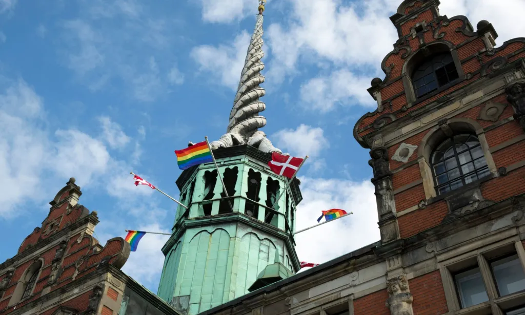Un drapeau de la fierté flotte aux côtés du drapeau danois devant la Børsen, l'ancienne bourse de Copenhague, la capitale du Danemark.
