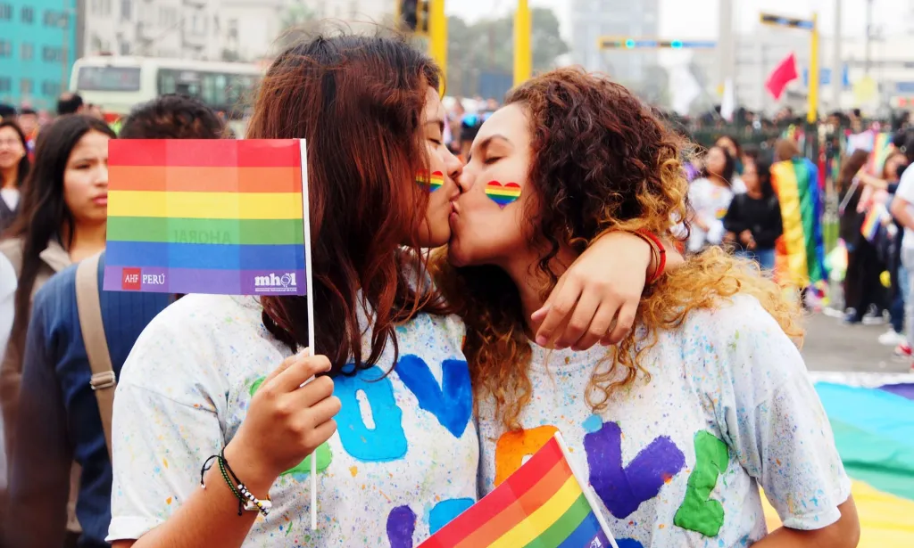 Un couple s'embrasse en brandissant des drapeaux arc-en-ciel de la fierté LGBTQ+ lors d'une marche au Pérou où les défenseurs appellent à des lois sur le mariage homosexuel, à protéger les personnes queer de la discrimination et plus encore.