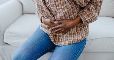 Personne tenant son abdomen avec douleur.