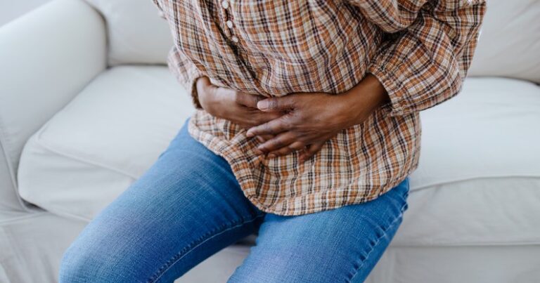 Personne tenant son abdomen avec douleur.