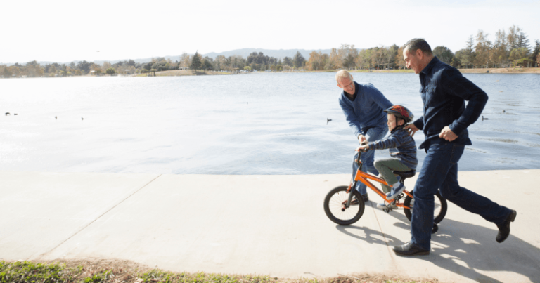 Un couple gay apprend à son enfant à faire du vélo.